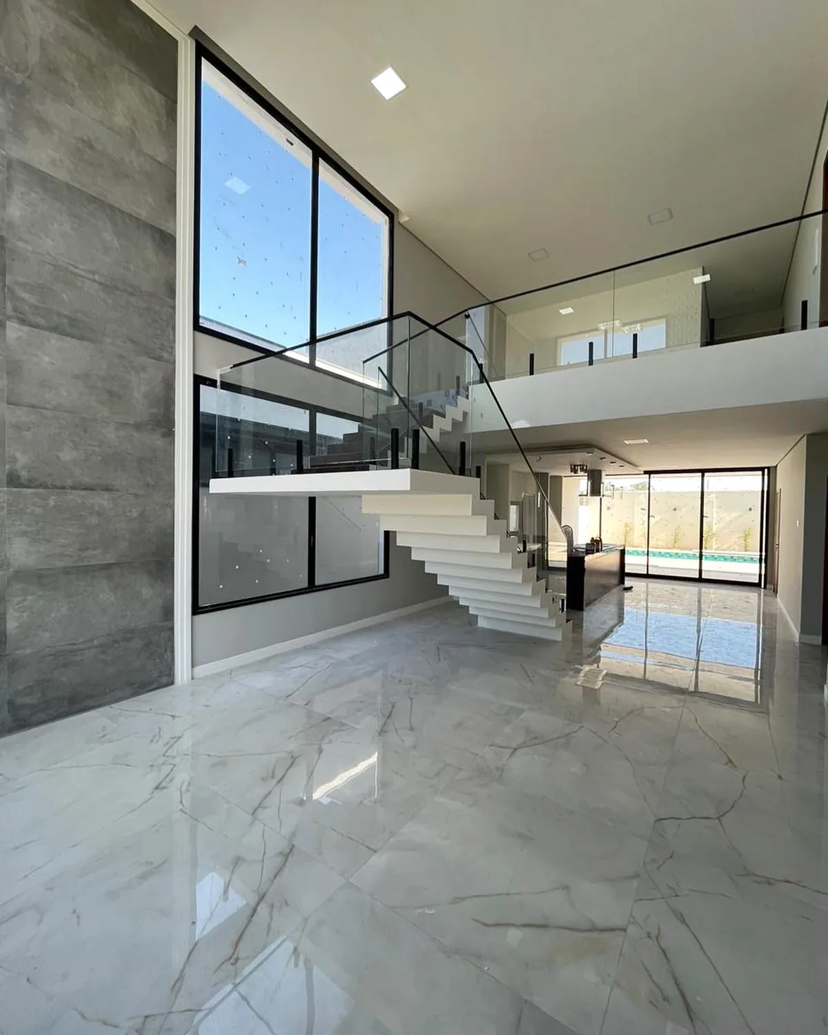 Interior de dois pavimentos com janelas amplas e guarda-corpo de vidro