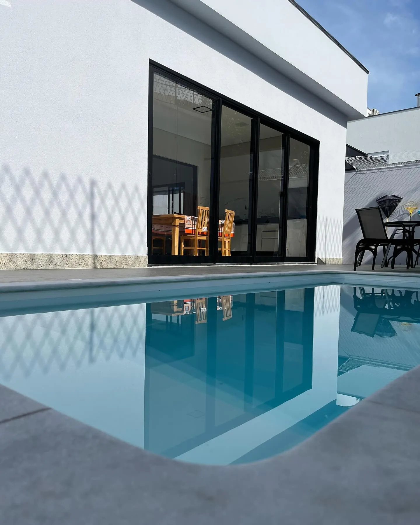 Área externa com piscina e portas de correr de perfis escuros