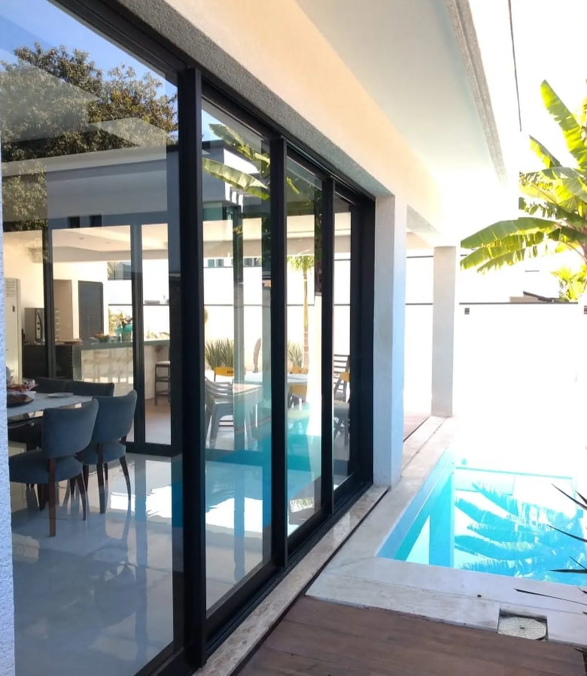 Portas de vidro com perfis escuros voltadas para a piscina